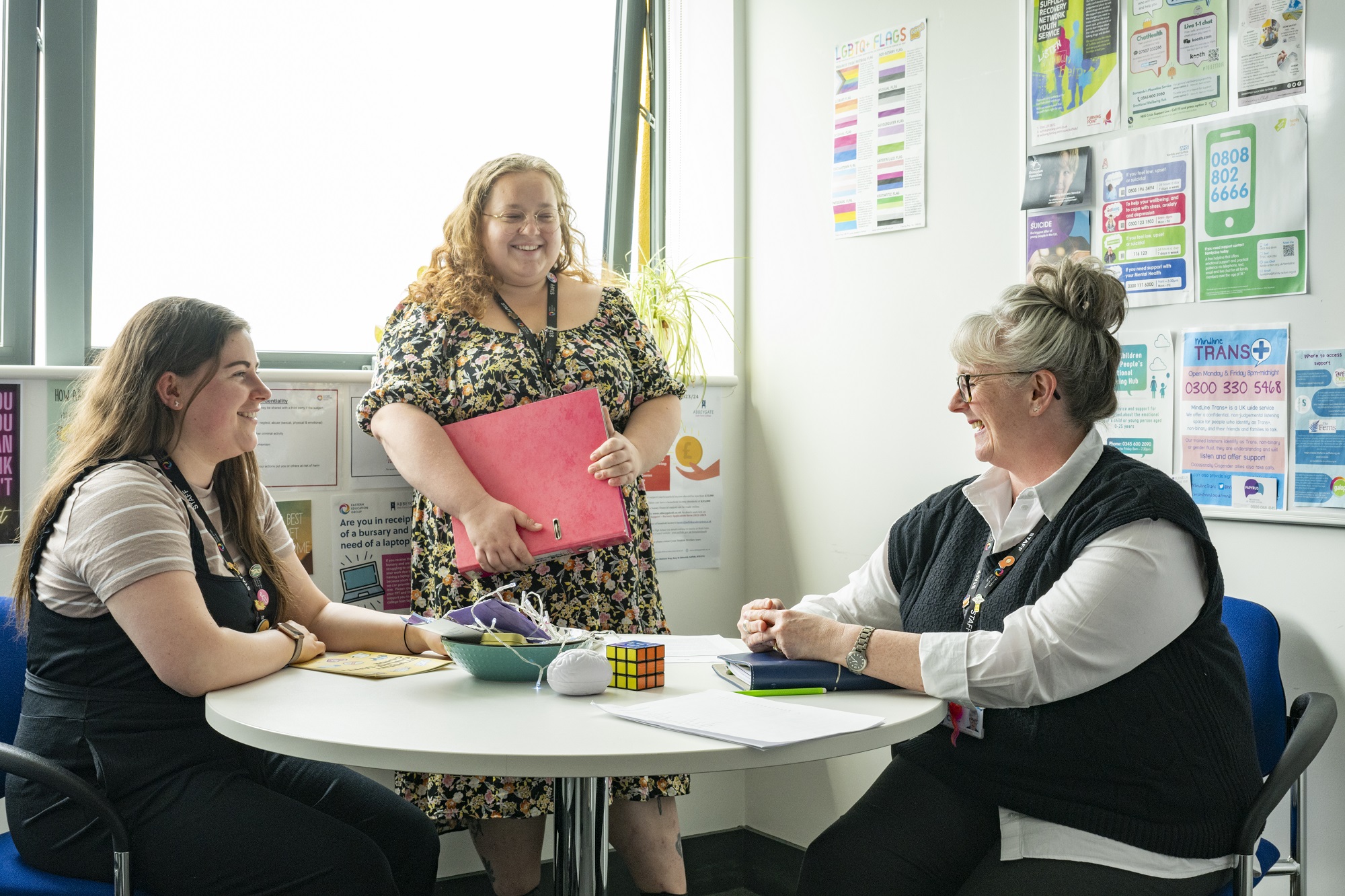 Staff members sat around a table chatting, an illustration
