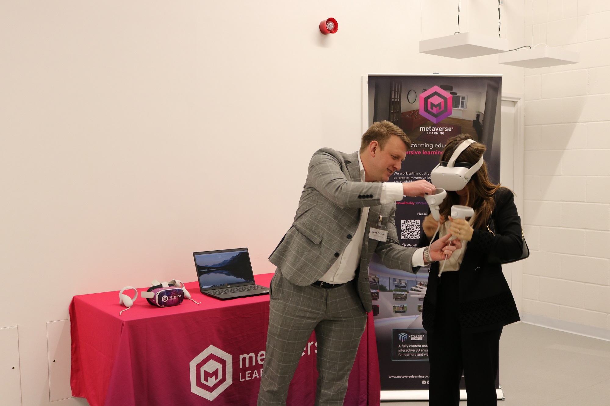 A gentleman alongside a lady who is wearing a virtual reality headset.